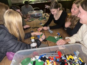 Gruppenteilnehmer arbeiten zusammen an einem Tisch mit LEGO-Steinen, während sie kreatives Stop-Motion-Filmprojekt umsetzen.
